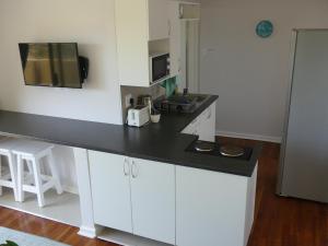 a kitchen with white cabinets and a black counter top at Rose and Ale Self Catering Units in Gonubie