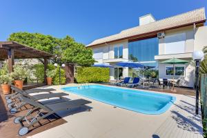 uma piscina com espreguiçadeiras e uma casa em Pousada Ilha Faceira em Florianópolis