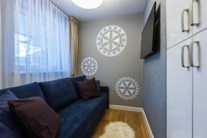 a living room with a blue couch and a tv at Apartament Przy Krupówkach Odkryj Zakopane in Zakopane