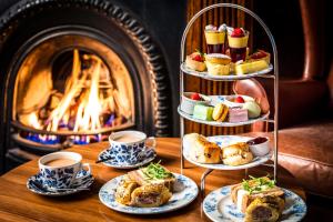 a table topped with plates of food next to a fireplace at The Borrowdale Hotel in Keswick