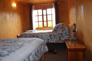 um quarto de hotel com duas camas e uma janela em Los Mañíos Del Queulat Puyuhuapi em Puyuhuapi