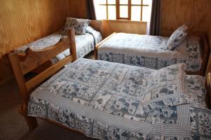 a room with two beds and a bedskirts at Los Mañíos Del Queulat Puyuhuapi in Puerto Puyuhuapi