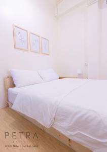 ein Schlafzimmer mit einem weißen Bett mit zwei Bildern an der Wand in der Unterkunft Petra Poshtel Donmuang in Bangkok