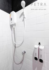 a shower in a white tiled bathroom at Petra Poshtel Donmuang in Bangkok
