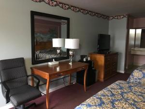 Habitación de hotel con escritorio, silla y espejo en Village Inn en Lovingston