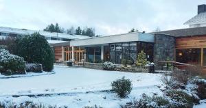 a house with snow on the ground in front of it at Coylumbridge Hotel in Aviemore