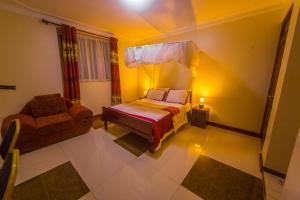 ein Schlafzimmer mit einem Bett und einem Stuhl darin in der Unterkunft Hotel Royal Nest Entebbe in Entebbe