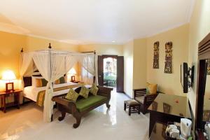 a bedroom with a canopy bed and a living room at Adi Dharma Hotel Kuta in Kuta