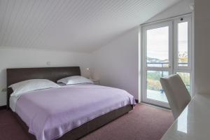 a white bedroom with a large bed and a window at Beach Guesthouse Mediteran in Podstrana