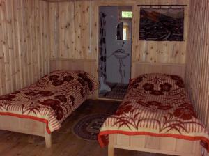 2 łóżka w pokoju z drewnianymi ścianami w obiekcie Guest House Mirgvela w mieście Omalo