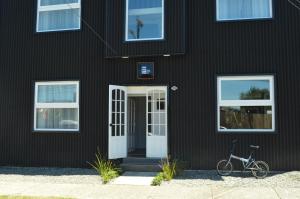 una bicicleta estacionada frente a una casa negra en Hotel Nueve Ríos, en Valdivia