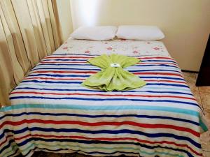 a bed with a striped blanket with a dress on it at Hotel Do Oeste in Palmitos