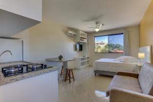 a living room with a bed and a kitchen at Pousada Praia dos Ingleses in Florianópolis