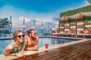 two women sitting on a bench in front of a pool of water at Nomads Hotel & Rooftop Pool Cancun in Cancún