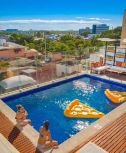 Dos mujeres en una piscina en un complejo en Nomads Hotel, Hostel & Rooftop Pool Cancun en Cancún