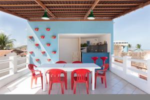 a white table and red chairs on a balcony at BRECHA HOSTEL & ROOFTOP - Maragogi in Maragogi