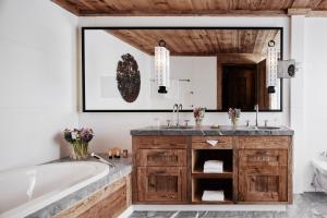 un bagno con vasca e un grande specchio di The Alpina Gstaad a Gstaad
