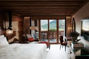 una camera con letto e un soggiorno con balcone di The Alpina Gstaad a Gstaad