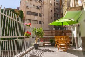 un patio con una mesa y una sombrilla verde en Central Terrace Modern Apartment, en Tesalónica