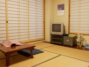 a living room with a table and a tv at Kakiya Ryokan in Kamakura