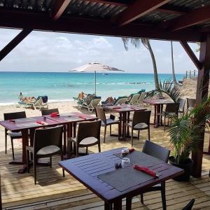 a group of tables and chairs on the beach at Studio Luxe vue mer in Le Gosier