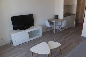 een woonkamer met een tv en een tafel en stoelen bij Studio Oxford in Chevigny-Saint-Sauveur