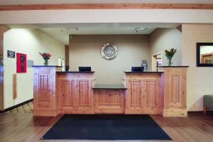 Hawthorn Suites by Wyndham Minot في مينوت: غرفة انتظار مع خزائن خشبية وزهور