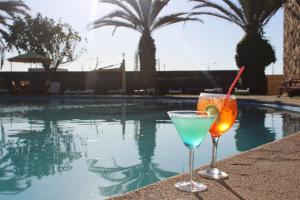 dos cócteles sentados en una cornisa junto a una piscina en Hotel La Serena Plaza, en La Serena