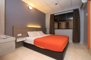 a bedroom with a large bed with an orange blanket at Yellow Mansion Hotel in Melaka