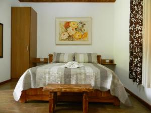 Un dormitorio con una cama con una mesa y una pintura en Chalés Luar da Serra, en Santo Antônio do Pinhal
