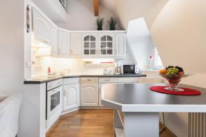 a kitchen with white cabinets and a bowl of fruit on a counter at Comeback Apartment Central in Dresden