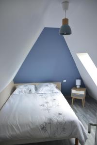 a bed in a room with a blue wall at GITE "COTE JARDIN" in Vannecrocq