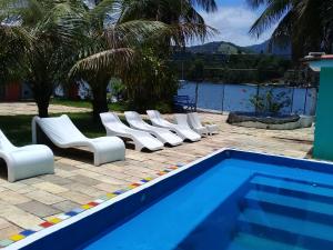 a row of white chairs sitting next to a swimming pool at ANGRA PIER 99 Suites in Angra dos Reis