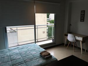 a bedroom with a bed and a desk and a window at Roosevelt 1681 in Buenos Aires