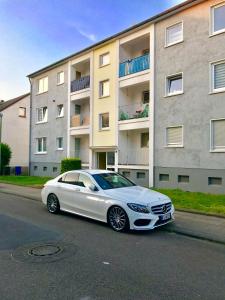 une voiture blanche garée devant un bâtiment dans l'établissement Aparts House - Balkon-WiFi-Kitchen, à Essen
