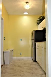 a kitchen with yellow walls and a refrigerator at The Big Island Hostel in Hilo