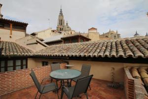 Un patio con una mesa y sillas en un tejado. en Apartamentos Las Teresitas junto a la Catedral, en Toledo