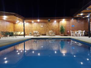a swimming pool at night with a table and chairs at Hotel Barba Lá in Combarbalá