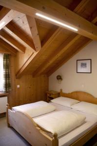 two beds in a room with wooden ceilings at Casa Tödi Restaurant Hotel in Trun