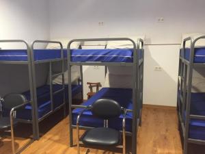 a room with three bunk beds and two chairs at El Pajar de Oncina Albergue Peregrinos in Oncina de la Valdoncina