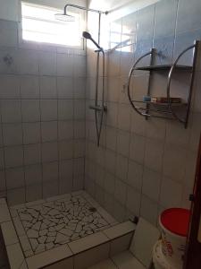 a tiled bathroom with a shower with a window at chez jojo in Baie-Mahault