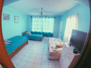Habitación azul con 2 camas y TV en Cabaña Pichidangui, en Pichidangui