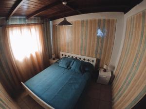 1 dormitorio con cama con sábanas azules y ventana en Cabaña Pichidangui, en Pichidangui