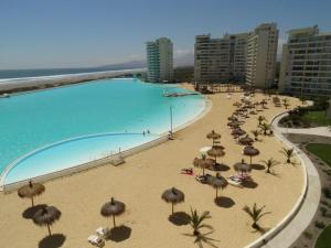 una playa con sombrillas y una piscina en apartamento, en La Serena