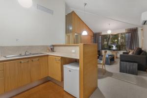 a kitchen with a sink, a refrigerator, and a table at Airport International Motel Brisbane in Brisbane