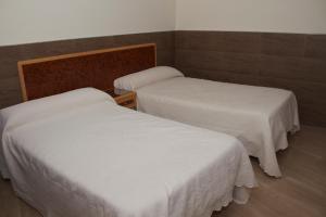 two beds in a room with white sheets at Domus Viatoris in Sahagún