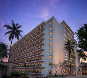 a large white building with palm trees in front of it at Sokha Beach Resort in Sihanoukville