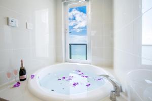 uma casa de banho branca com uma banheira e uma janela em Costa Bella Condominium Resort em Motobu