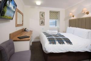 ein Hotelzimmer mit Bett, Schreibtisch und Fernseher in der Unterkunft The Inveraray Inn, BW Signature Collection in Inveraray
