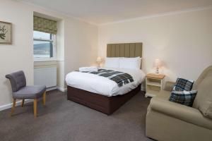 ein Schlafzimmer mit einem Bett, einem Stuhl und einer Couch in der Unterkunft The Inveraray Inn, BW Signature Collection in Inveraray